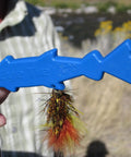 Hand holding blue Eye Tie Fly Threader With Magnetic 3 Funnel System For Hook Sizes 3 To 24 in outdoor setting.