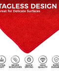 Close-up of red microfiber towel showcasing tagless design with icons for softness, scratch resistance, quick drying, quality, durability.