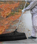 Heavy Duty Outdoor Angle Broom With 20 Inch Wide Base And 51 Inch Extended Handle Sweeper featuring stiff bristles clearing leaves on a driveway.