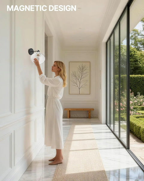 Woman adjusting HOJOYRI Black Recharge Battery Operated Wall Sconces Set of Two with Remote in modern hallway.