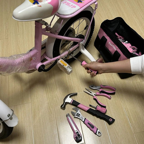 Using Pink Tool Set 218-Piece Home Improvement Kit For Women to repair a bike with tools spread on floor.