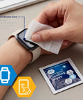 Close-up of a hand wiping a smartwatch screen with a premoistened lens and screen cleaning wipe; wipe packet nearby.