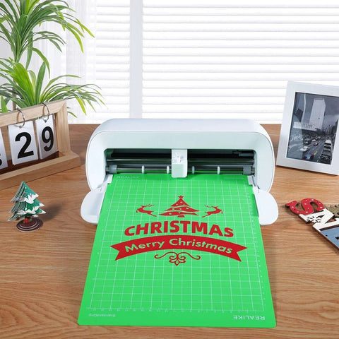 Front view: REALIKE 8.5x12 cutting mat, green with Christmas design, loaded in a white cutting machine.