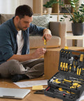 Man using screwdriver from 339 Piece Tool Set For Home And Auto Repair, Comprehensive Hand Tool Kit With Wrenches, Sockets, Pliers, Screwdrivers, Hammer, Tape Measure, Drill Bits, Hex Keys, And More For DIY Projects And Weekend Fixes on wood furniture.