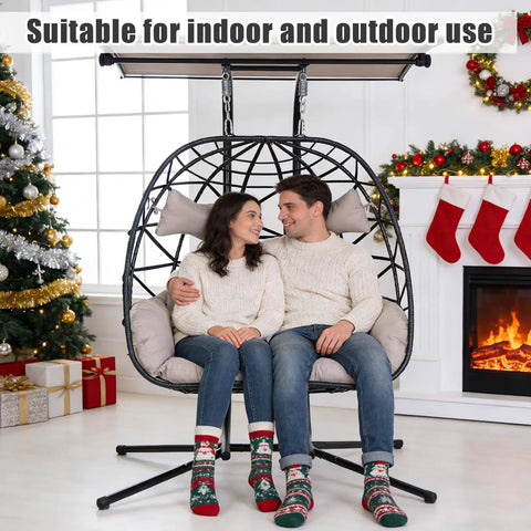 Couple sitting on Double Hanging Egg Chair With Canopy And Stand For Two People, 700 lbs capacity, indoor holiday setting