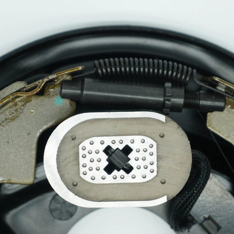 Close-up view of two 10-inch electric trailer brake magnets on backing plate for Dexter-type brakes with coil springs.