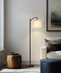 Arc Shaped LED Floor Lamp With Hanging Shade For Living Rooms And Offices Sleek Modern Lighting With Sturdy Marble Base Lit Reading Light Mid Century Farmhouse Style Black next to a couch.