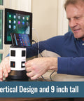 Man using Spin Power Tower Surge Protector With 4 Outlets And 6 USB Ports to charge tablet and phone on built-in shelf.