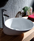 USZWBY Bathroom Vessel Sink Bathroom Vessel Sink Oval Above Counter White Porcelain Ceramic Bowl Basin, No Overflow Hole, Ceramic Sink Only Bathroom Sink on wooden countertop with chrome faucet.