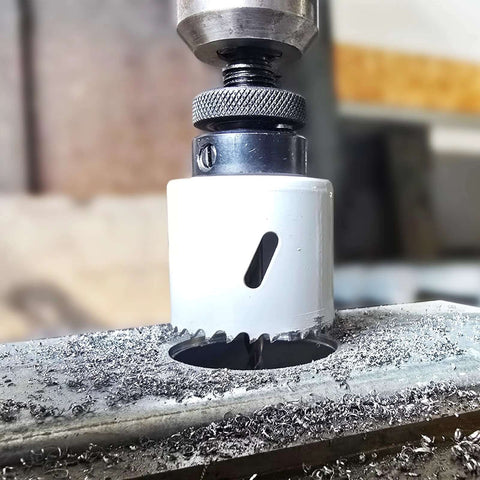 Maycraft hole saw bit in drill chuck; white housing with serrated cutting teeth cutting metal.
