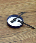 Two black scrapers on a white dish, part of the 17 Piece Herb Grinder Cleaning Kit With Scrapers Spoons Long And Short Brushes And Storage Box