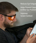 Man wearing blue light blocking computer glasses with SCT orange lens, using a tablet. Text highlights benefits like eye strain reduction.
