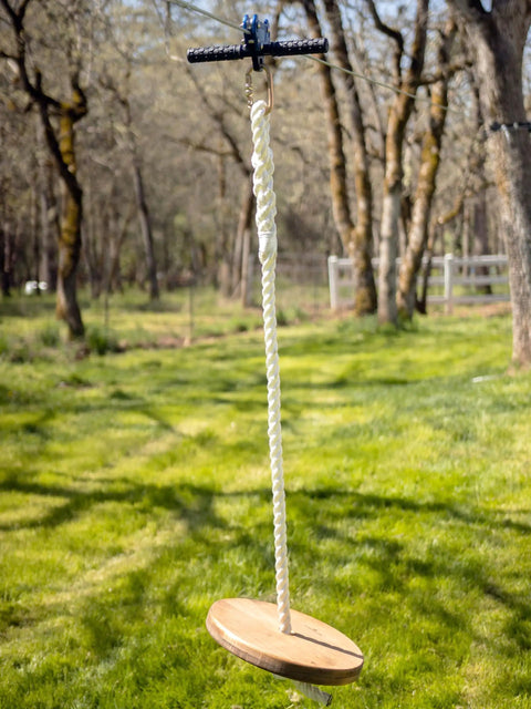 Zip Line Kit 150 Feet With Seat And Carabiner Heavy Duty One Quarter Inch Galvanized Cable Backyard Fun For Families Supports Up To 350 Lbs Weather Resistant Easy Setup For Hours Of Outdoor Adventure shown installed in a backyard with wooden seat and rope hanging low.
