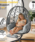 Woman sitting in grey Hanging Egg Chair With Adjustable Footrest And Stand For Indoor And Outdoor Use Wicker Swing Chair With Cushion, holding a cat.
