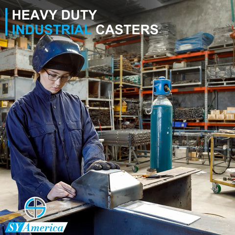 Worker in protective gear assembling heavy duty industrial casters in a workshop setting with equipment in the background.