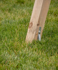 Wooden swing set leg anchored in grass using Playset Anchor Kit For Swing Sets Heavy Duty Ground Anchors That Keep Your Set Rock Solid Stationary And Safer For Outdoor Fun Easy Install Swing Set Hardware To Secure Play Equipment And Protect Your Kids