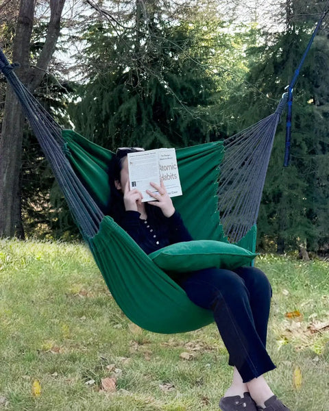 Person sitting in a dark green Two Cushions Included Hammock Chair With Soft Cotton Handwoven Fabric Indoor Outdoor Hanging Rope Swing.