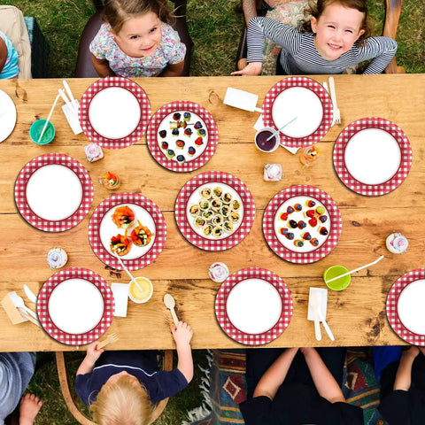48 Pack Red And White Checkered Disposable Paper Plates For Backyard Kickbacks arranged on a wooden table with food and drinks.