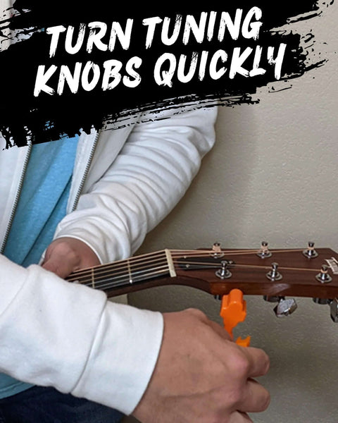 Guitar 3-in-1 tool (orange) clamped to headstock as a person winds strings on a wooden guitar.