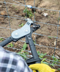 Person using Torq Wire Tensioning Tool with built-in gauge to tighten garden trellis wire, focus on tool against fence.