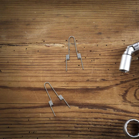 Ditch Your Wonky Flip Lid With These Rock Solid Stainless Steel Torsion Springs And Make DIY Repairs A Breeze For Any Trash Can In The Kitchen Or Home; two springs on wood