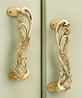 Peacock decorative brass door handles in antique gold finish on cabinet doors.