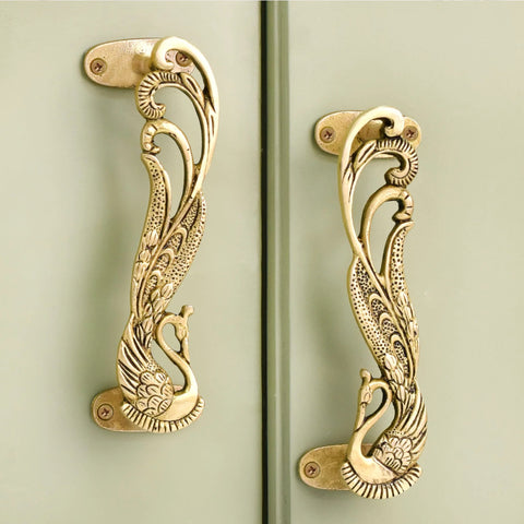 Peacock decorative brass door handles in antique gold finish on cabinet doors.