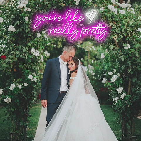 Bride and groom under arch with 'you're like really pretty' neon sign, perfect for wedding decor. Like Really Pretty Neon Sign For Wall Decor Pink Light Up Sign Dimmable For Wedding Engagement Party Birthday Bedroom Bar Club 29.5 By 12.6 Inches Great For Home Decor Parties Events.