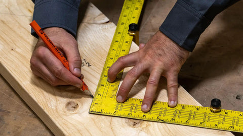 Hands using Beefy Brass Stair Gauge Set For Framing And Carpentry Squares 2-Piece for precise right-angle cuts on wood