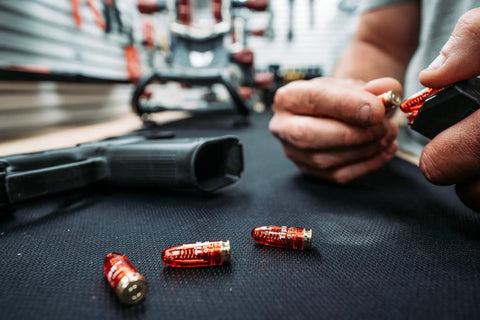 Close-up of 9mm Pistol Snap Caps Reusable Dummy Rounds for Safe Dry Fire, Trigger Tuning, on a black surface with hand loading a magazine.