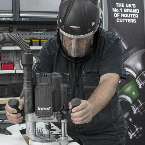 Badass Powered Air Respirator And Hearing Protection Bundle For Woodworking Shops Featuring Full Face Impact Shield Heavy Duty Dust Filters And Integrated Ear Guards Built Tough For Sanding Routing And Turning in use on router machine.