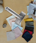 Heavy Duty Metal Sewing Bed Cloth Clamps For Hemming And Fabric Quilting Workholding Tools on a work table with fabric swatches.
