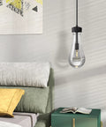 Modern light bulb pendant lamp over a bed with colorful pillows in a stylish bedroom with abstract artwork on the wall.