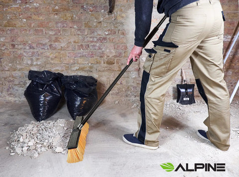 Real Deal Heavy Duty Push Broom With Long Handle Made To Crush Daily Grime On Smooth Floors Sweeps Sand Mud Leaves And Water Easy Without Breaking A Sweat In Bright Yellow 18 Inches Wide cleaning debris in a garage.