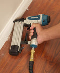 Rock Solid 18 Gauge 2 Inch Brad Nailer Kit in use for baseboard installation, featuring ergonomic grip and air hose connection.