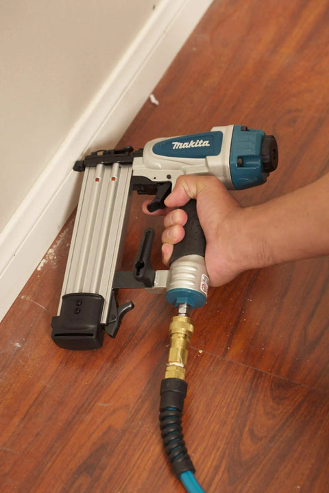 Rock Solid 18 Gauge 2 Inch Brad Nailer Kit in use for baseboard installation, featuring ergonomic grip and air hose connection.