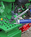 Side view of Lincoln lever-action grease gun with blue handle and 18-inch hose used on green agricultural equipment.