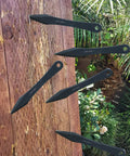 Six Pack 9.4 Inch No Spin Throwing Spikes Set in Durable 420HC Stainless Steel embedded in a wooden target outdoors.