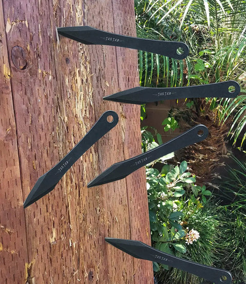 Six Pack 9.4 Inch No Spin Throwing Spikes Set in Durable 420HC Stainless Steel embedded in a wooden target outdoors.