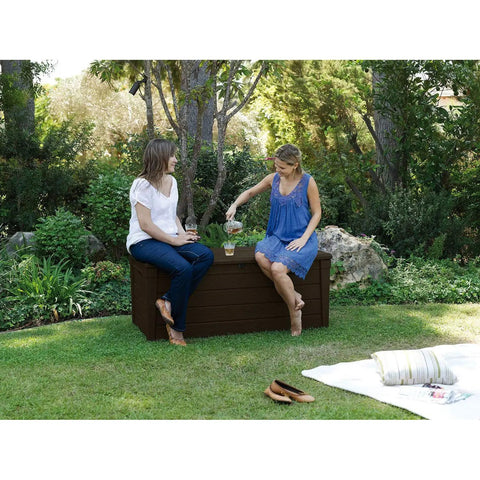 Two people sitting on Lockable 120 Gallon Outdoor Storage Deck Box For Patio Backyard And Garden In Brown Waterproof Plastic Bench