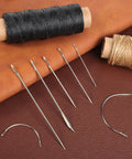 Two Roll Waxed Thread Sewing Kit With Seven Hand Needles For Diy Home Upholstery, Carpet, Canvas, Bags And Sofa Repair, Heavy Duty Darning Set In Black And Khaki For Quick Fixes displayed with needles on brown leather background.