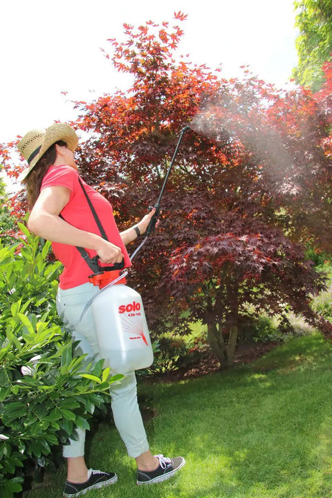 Person using 1-Gallon Handheld Farm and Garden Sprayer with Easy Fill Funnel Top and Large Secondary Opening in garden