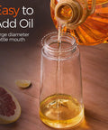 Smooth Operator Sixteen Oz Glass Olive Oil Spray Bottle With Dual Pour And Sprayer Function Drip Free Build For Grilling Roasting And Healthy Cooking Bpa Free Matte Black Kitchen Ace pouring oil into a large mouth glass bottle.
