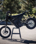 IN10 Electric Dirt Bike With 2600W Peak Motor, 40 MPH Top Speed, 48V 23Ah Battery, Full Hydraulic Brakes And Suspension, Off Road Mountain Ebike For Teens And Adults, Ready To Rip Trails, black side view on stand