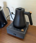 Game Changing Two In One Coffee Station Organizer With Heavy Duty Kettle Stand And V60 Paper Filter Bin For Smooth Pour Over Brewing Rig And Clean Counter Hacks showing matte black kettle on an electric stand.