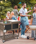 80 Quart Rolling Patio Cooler With Bottle Opener And Shelf Standing Ice Chest With Blackboard For Outdoor Gatherings Taupe Brown in use at a party