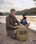 Man with Fishing Backpack 45L with Rod Holders, Water Resistant Tackle Storage Pack, at riverbank with fishermen