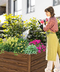 Woman watering Two Pack 4x2x2 Ft Raised Garden Beds Outdoor Galvanized Planter Boxes filled with flowers and herbs in a backyard