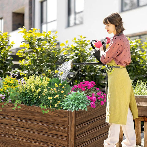 Woman watering Two Pack 4x2x2 Ft Raised Garden Beds Outdoor Galvanized Planter Boxes filled with flowers and herbs in a backyard