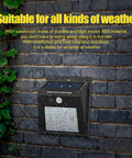Solar Motion Sensor Outdoor Lights 30 LED 4 Pack With Motion Activated Security Lighting No Fuss Solar Powered Exterior Wall And Gutter Sconce Lamps For Home Safety Weatherproof Black on brick wall in rain